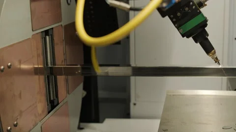 Automated CNC laser cutting machine processing a square metal pipe with bright Stock Footage 345894401