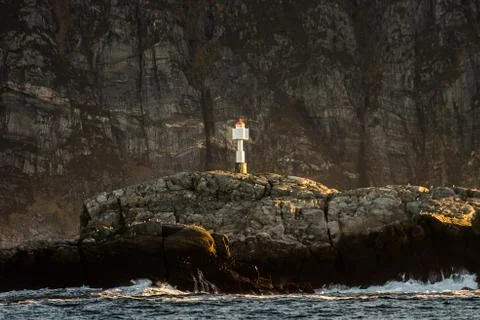 Automated lighthouse centered in frame standing on rock in front of steep nor Foto stock