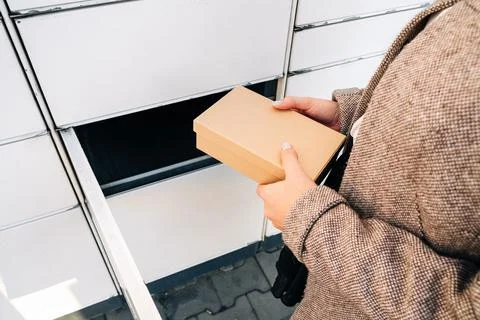 Automated locker. Parcel courier box in woman hands at post delivery automat  Foto stock