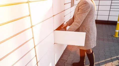 Automated locker. Parcel courier box in woman hands at post delivery automat  Foto stock