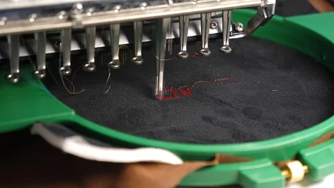 An automated machine embroiders pattern with red threads on a black cloth Stock Footage 108269588