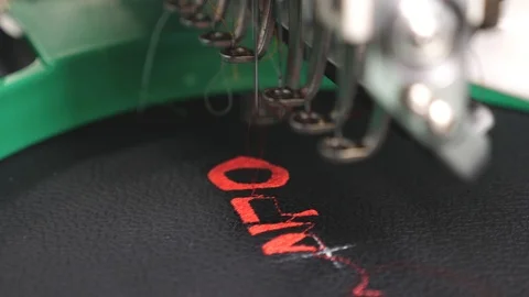 An automated machine embroiders pattern with red threads on black cloth. Robot Stock Footage 108877288