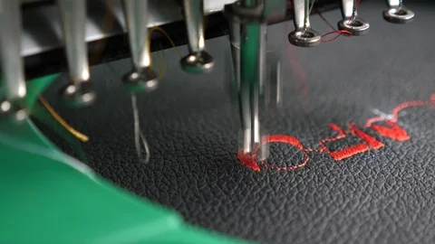 An automated machine embroiders pattern with red threads on black cloth. Robot Stock Footage 110823941