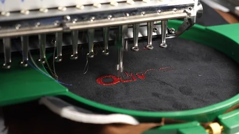 An automated machine embroiders pattern with red threads on a black cloth Stock Footage 111231545