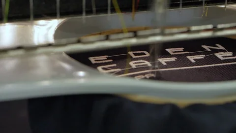 Automated machine embroiders pattern with white threads on black cloth- close up Stock Footage 115482321