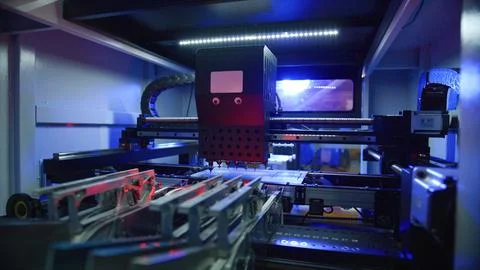 Automated machine processing components in factory with blue and red lights Stock Photos