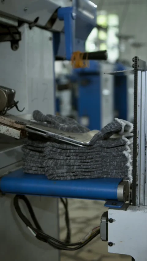 Automated machine stacks finished gloves after production. Textile factory Stock Footage 341356499