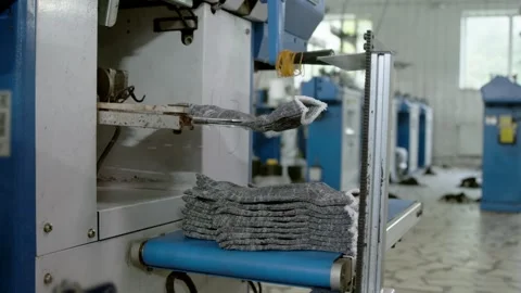 Automated machine transfers finished work gloves onto growing stack. Industrial Stock Footage 341355289