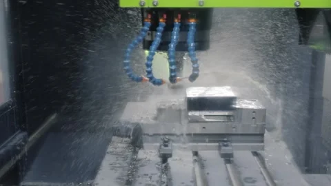 Automated milling machine precisely cutting metal block with coolant spray .. Stock Footage 337349380