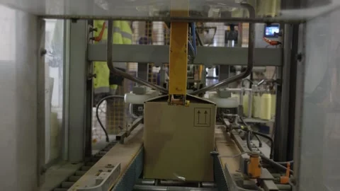 Automated packaging machine sealing a cardboard box on a conveyor belt Stock Footage 335351614