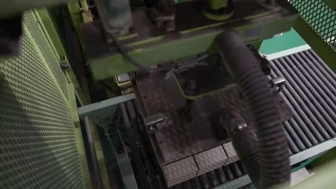 Automated stacker lowers onto a block of tan ceramic tiles behind a wire mesh Vídeo Stock 346737768