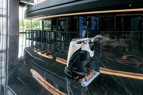 Automatic AI cleaner mopping floor inside of a modern office building. Fotos de archivo