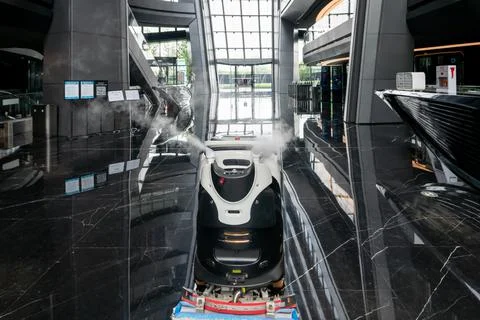 Automatic AI cleaner mopping floor inside of a modern office building. Fotos de archivo