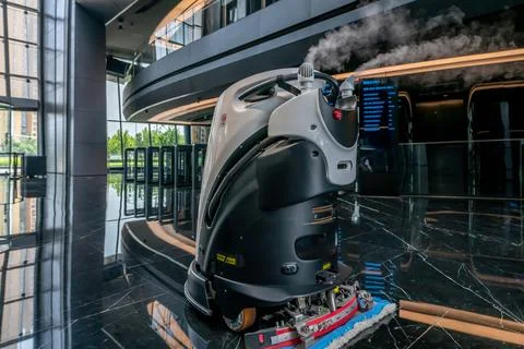 Automatic AI cleaner mopping floor inside of a modern office building. Fotos de archivo