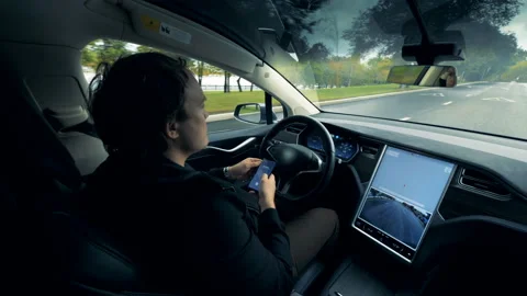 An automatic automobile is moving along the road with its driver sitting inside Stock Footage 98595932
