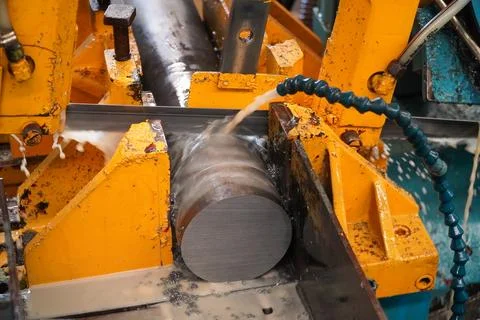 Automatic band saw machine cutting the metal rod with water base coolant me.. Stock Photos