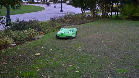 Automatic battery-powered robotic lawnmower moves along a city park Vídeo Stock 169713769