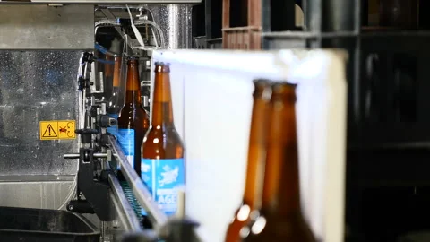 Automatic Beer Bottling Line. Queue of ready filled bottles on the conveyer Stock Footage 99434774
