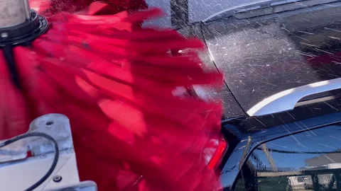 Automatic car wash brush cleaning black vehicle surface Stockbeeldmateriaal 332790640