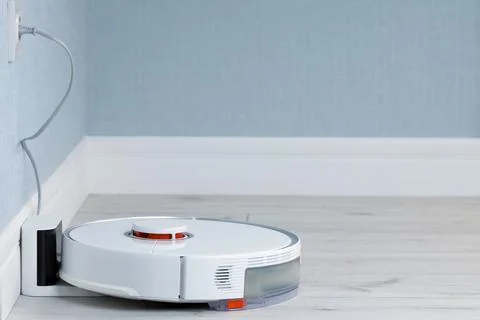 Automatic charging of the robot vacuum cleaner. Smart Home Concept Stock Photos