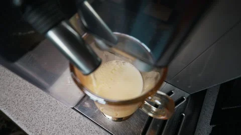 Automatic Coffee Machine Dispensing Frothy Milk Into Amber Glass Mug Video stock 339180609