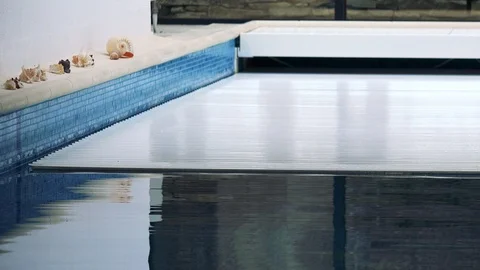 An automatic cover rolls over an indoor swimming pool 库存影片 85782818