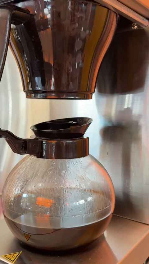 Automatic drip coffee maker brewing fresh filter coffee into a glass carafe in Stock Footage 345173544