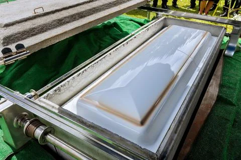 An automatic elevator is used to lower the coffin into a grave by means of a Stock Photos