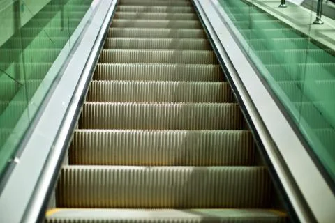 Automatic escalator. There are green glasses and yellow warning signs. Stock Photos