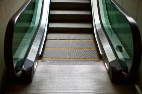 Automatic escalator. There are green glasses and yellow warning signs. Stock Photos