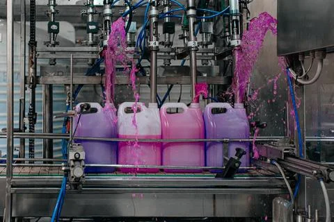Automatic filling machine pours into plastic PET bottles at modern beverage Stock Photos