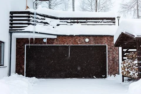 Automatic garage door of a cottage in a snowfall. Winter house with automatic Stock Photos