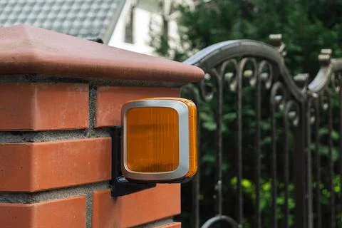 Automatic gate signal light with orange lens mounted on a brick pillar Stock Photos