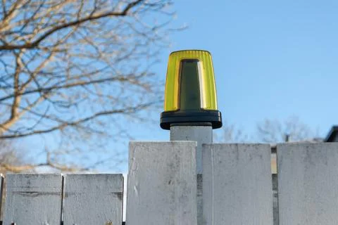 Automatic gate warning light on fence against blue sky Stock Photos