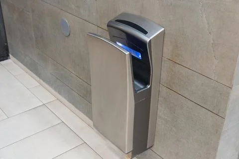 An automatic hand dryer installed in a contemporary bathroom setting promot.. Stockfoto's