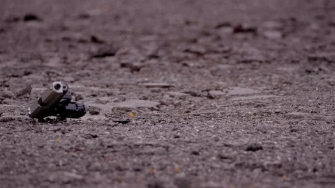 AUTOMATIC HANDGUN FALLS TO THE GROUND.  SLOW MOTION 180 FPS.  NEGATIVE SPACE. Stockbeeldmateriaal 103288663