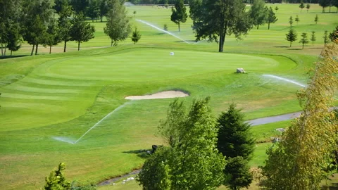 Automatic high-pressure water sprinkler at green golf course watering the grass. Stock Footage 255523485
