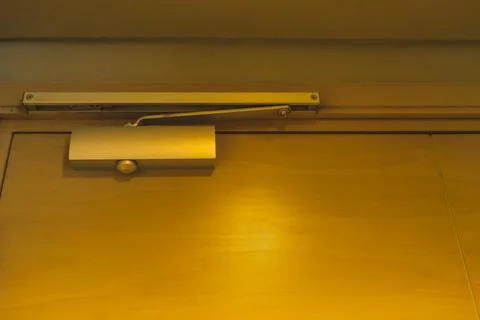 Automatic hydraulic door closer installed on a wooden door frame Stock Photos