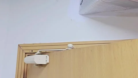 An automatic hydraulic door closer is mounted on a light wooden door, Video stock 339703973