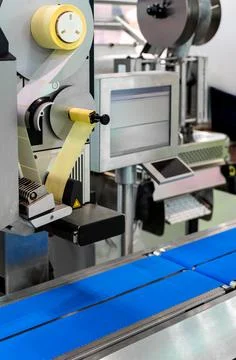 Automatic labeling machine on packaging line in modern factory Stock Photos