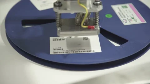 Automatic labeling machine. The robot sticks a label on the reel of components. Stock Footage 212382414