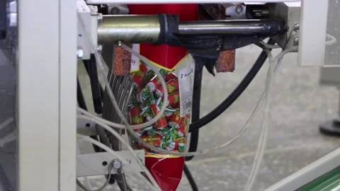 An automatic machine wraps the candies in transparent packaging Stock Footage 128643194