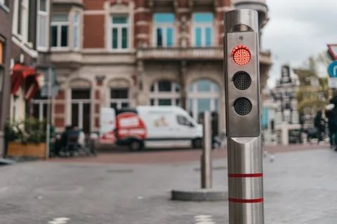 Automatic metallic bollard with red light with old city background Stock-Fotos