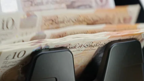 Automatic money counting machine processing 10 GBP British pound banknotes for Stock Footage 340023555