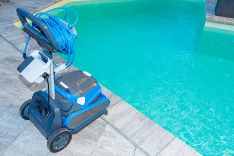 Automatic Pool Cleaner by the Poolside with Garden Background Foto stock