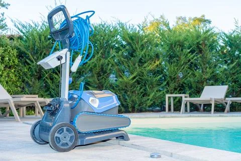 Automatic Pool Cleaner by the Poolside with Garden Background Foto stock