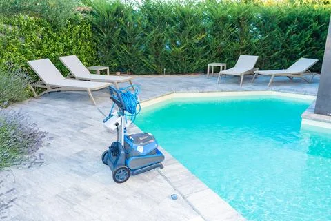 Automatic Pool Cleaner by the Poolside with Garden Background Foto stock