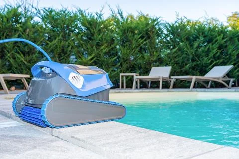Automatic Pool Cleaner by the Poolside with Garden Background Foto stock