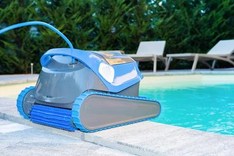 Automatic Pool Cleaner by the Poolside with Garden Background Foto stock