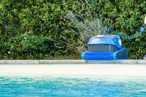 Automatic Pool Cleaner by the Poolside with Garden Background Foto stock